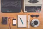 Office Desk With Computer, Supplies, Coffee Cup, Passport, Sungl Stock Photo