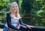 Blond Girl Leaning On Fence Near Water In Forest Stock Photo