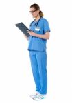 Female Surgeon With Stethoscope, Reading Report Stock Photo