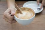 Hand On Hot Cup Of Coffee Latte Stock Photo