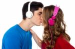 Young Couple Enjoying Music And Kissing Stock Photo