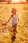 Happy Young Blonde Girl In White Dress With Straw Hat Running Th Stock Photo