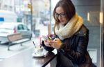 Beautiful Girl Using Her Mobile Phone In Cafe Stock Photo