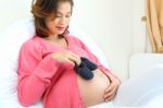 Portrait Of Pregnant Woman Holding Pair Of Black Shoes For Baby Stock Photo