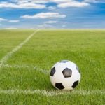 Soccer Ball On Soccer Field Against Blue Sky Stock Photo