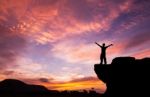 Silhouette Of A Man On The Rock At Sunset Stock Photo