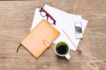 Orange Diary,blank Paper With Pencil, A Cup Of Coffee, Mobile Phone And Eye Glasses Stock Photo