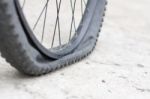 Bicycle Wheel With Flat Tyre On The Concrete Road Stock Photo