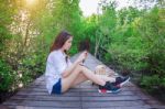 Girl Sitting Alone And Hand Holding Camera On A The Wooden Bridg Stock Photo