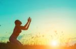 Silhouette Of Woman Praying Over Beautiful Sky Background Stock Photo