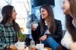 Three Young Woman Drinking Coffee And Speaking At Cafe Shop Stock Photo