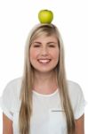 Smiling Woman Balancing An Apple On Her Head Stock Photo