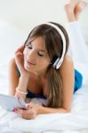 Beautiful Girl Listening To Music With Tablet On Sofa At Home Stock Photo