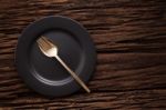 Black Empty Plate Fork Spoon On Wooden Table Background Stock Photo