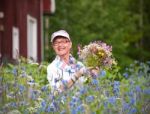 Elderly Smiling Woman In Her Garden With Flowers Stock Photo