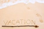 Inscription Of Vacation Written On Wet Yellow Beach Sand With Fo Stock Photo