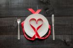 Red Ribbon In Heart Shape On Plate And Wooden Background Stock Photo