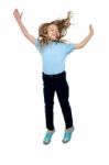 Delighted Young Girl Jumping High In The Air Stock Photo