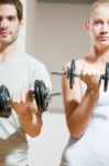 Man And Woman Lifting Dumbbell In Gym Stock Photo