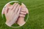 Hands Uniting In Glass Sphere On Grass Stock Photo