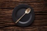 Black Empty Plate Fork Spoon On Wooden Table Background Stock Photo