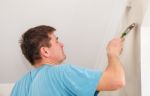 Young Worker Painting Wall With Glue Stock Photo