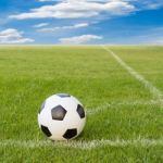 Soccer Ball On Soccer Field Against Blue Sky Stock Photo