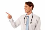 Smiling Male Physician Pointing Away Stock Photo