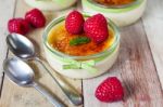 The Creme Brulee In Glass Dish With Mint And Raspberries Stock Photo