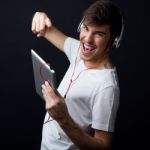 Young Beautiful Man Listening To Music. Isolated On Black Stock Photo