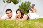 Beautiful Young Couple Lie Down On Grass Stock Photo