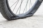 Bicycle Wheel With Flat Tyre On The Concrete Road Stock Photo