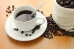 Cup Of Coffee And Bag Beans On Wooden Table Stock Photo