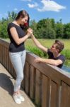 Young Man Offers Red Rose To Attractive Girlfriend On Bridge In Stock Photo