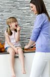 Young Woman And Little Girl Eating Carrots In The Kitchen Stock Photo