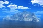 Rock Mountain Island In Ocean Under Cloud Blue Sky Stock Photo