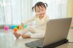 Little Asian Girl Play Laptop In Home Stock Photo