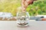 Close Up Of Hand Stacking Silver Coins On Glass Bottle Stock Photo