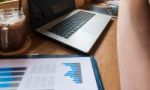 Coffee Cup  On A Table With Laptob And Graph Finance Diagram In Stock Photo