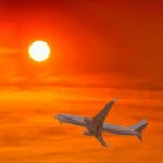 Commercial Airplane Flying At Sunset Stock Photo