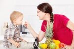 Mother Feeding Child In Kitchen Stock Photo