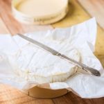 Camembert Cheese Wrapped In Paper With Vintage Knife On Wooden T Stock Photo