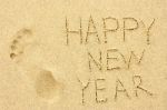 Inscription 'happy New Year' And Human Footprint In The Sand On Stock Photo