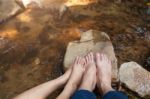 Feet Of Couple Sitting On The Stone Near River Stock Photo