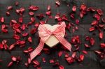 Wrapped Gift  With A Red Bow Surrounded By Dried Petals Stock Photo