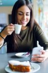 Beautiful Girl Using Her Mobile Phone In Cafe Stock Photo