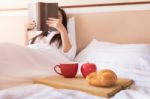 Woman Reading Book  And Drinking Coffee On Bed During The Mornin Stock Photo