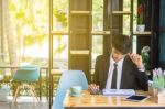 Business Man Sitting On A Calculator To Figure Out In A Coffee S Stock Photo