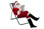 Kris Kringle Relaxing And Using Electronic Tablet Stock Photo