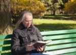 Haired Elderly Man Reading A Book Sitting On A Bench In City Par Stock Photo